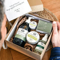 Gift box with skincare products and a card on a wooden surface